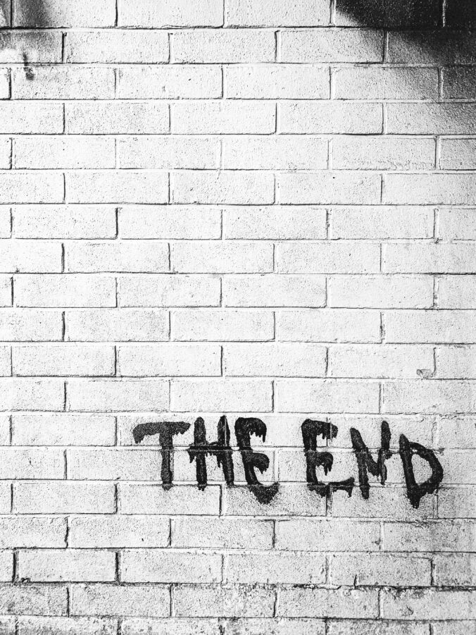 A silhouetted brick wall reads "the end" in spray paint in the bottom right corner